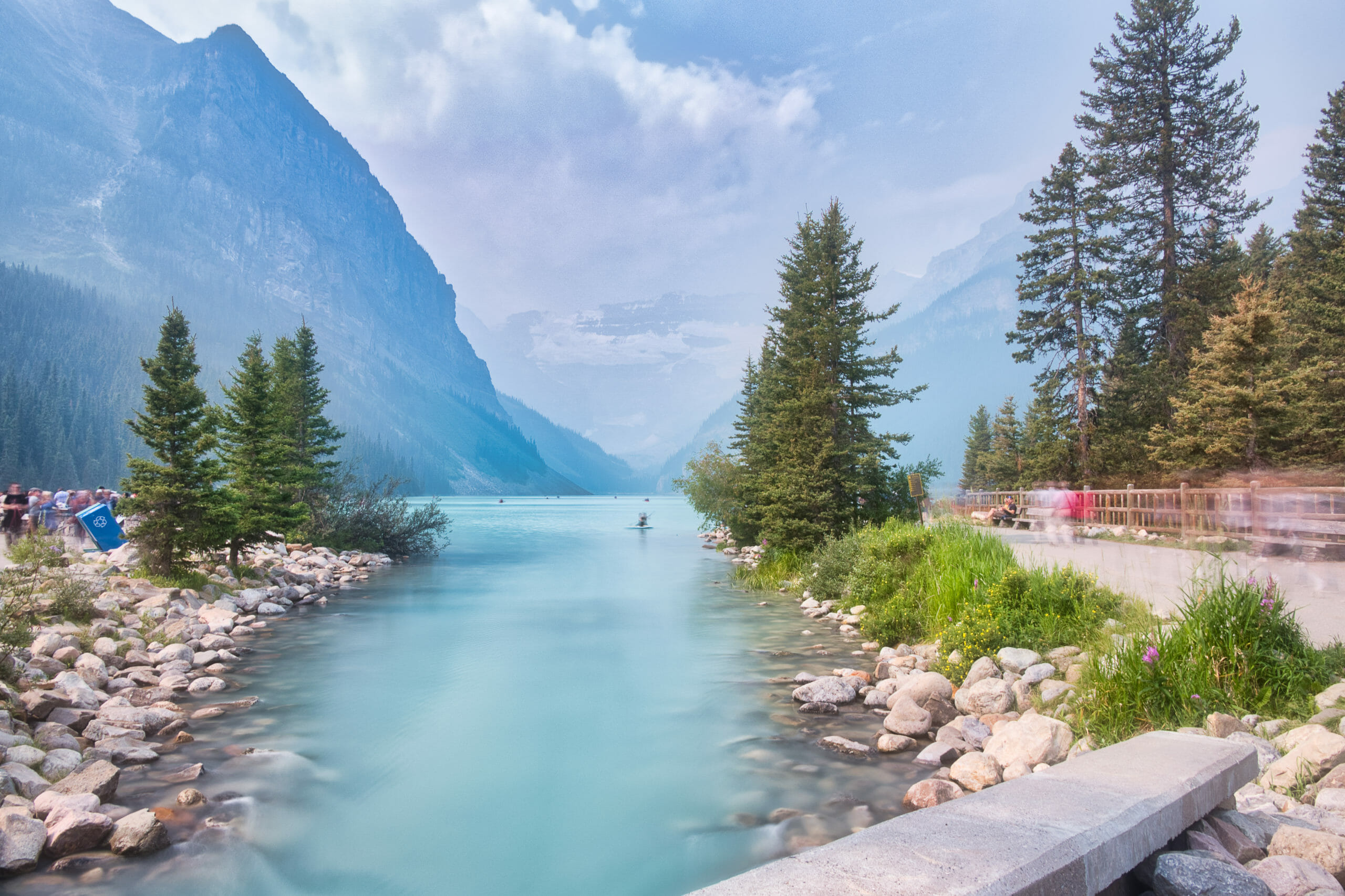 Tourists walking around at Lake Louise with obscured glacier and smoky skies from summer wildfires