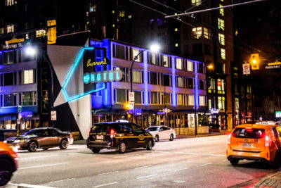 Taxis going by at Helmcken and Burrard at night in downtown Vancouver facing Burrard Hotel and Burgoo Restaurant