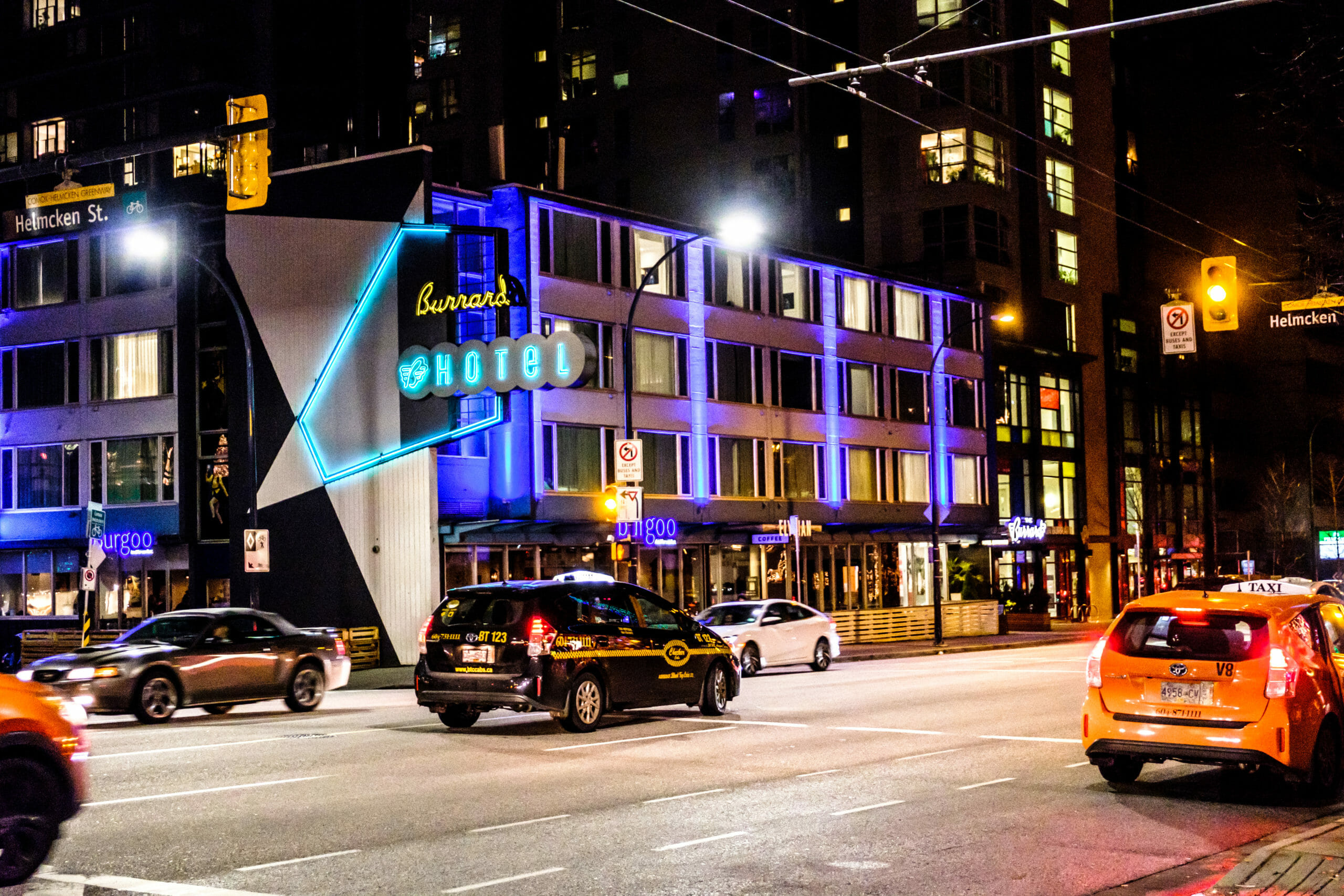 Taxis going by at Helmcken and Burrard at night in downtown Vancouver facing Burrard Hotel and Burgoo Restaurant