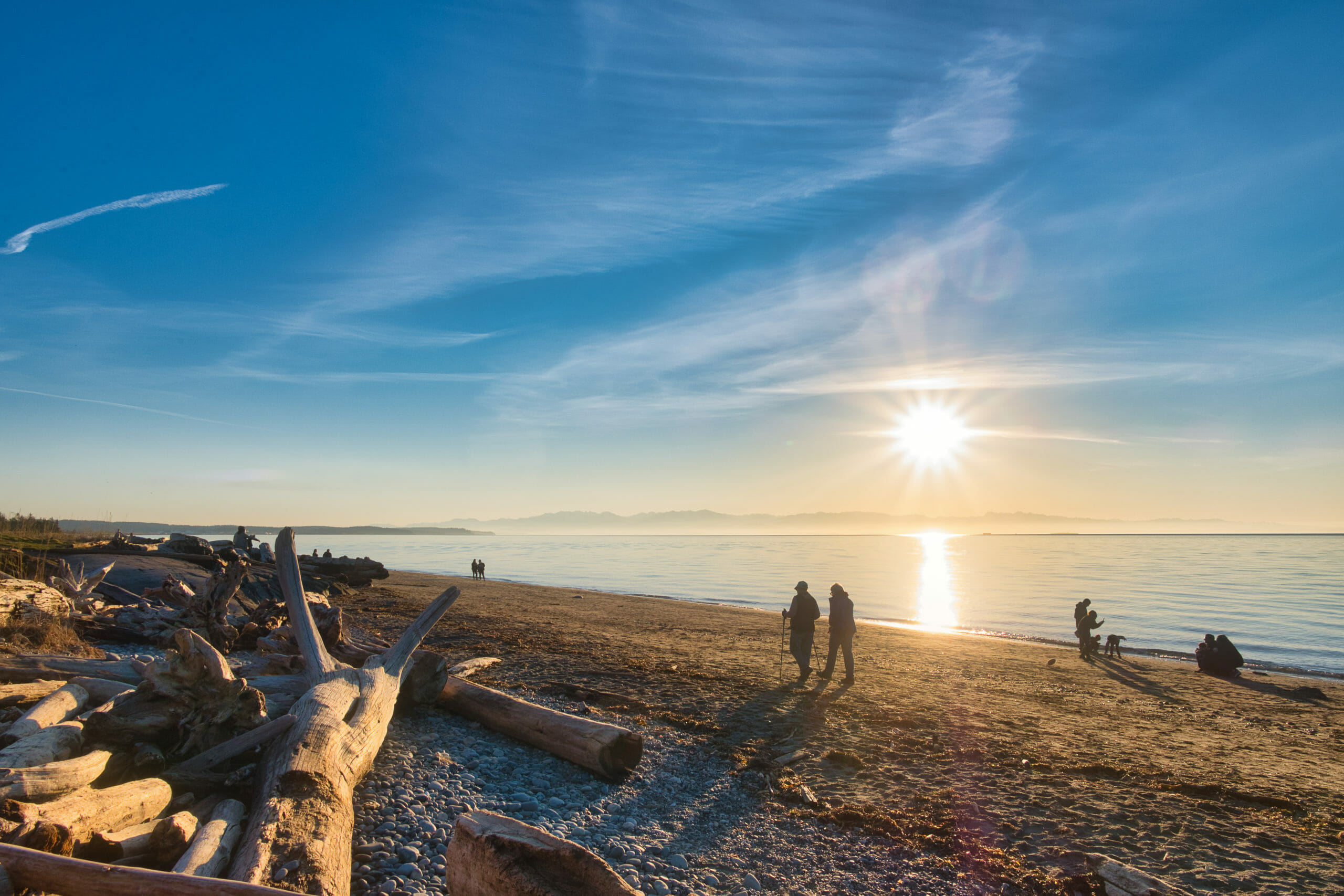 Families and children out for a stroll at sunset on clear sunny day at Deception Pass beach