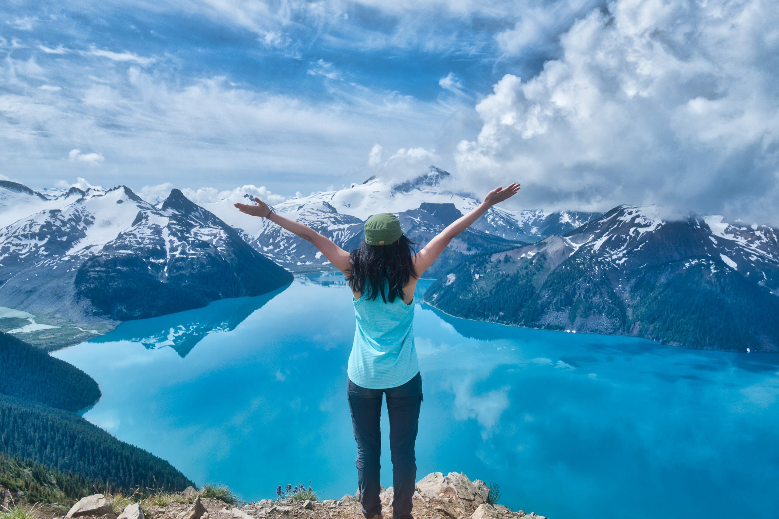 Female hiker enjoying top of Panorama Ridge overlooking Garibaldi Lake and mountain ranges in Garibaldi Provincial Park