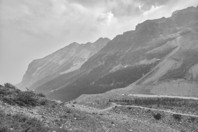 Gradient of mountains in black and white on Plain of Six Glaciers trail with smoky and cloudy skies from summer wildfires