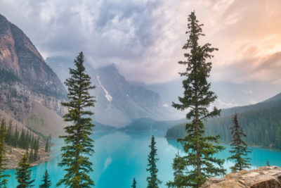 Moraine Lake view from Rockpile Trail with mix of gray and golden skies from wildfire smoke, thunderstorm clouds, and sunset