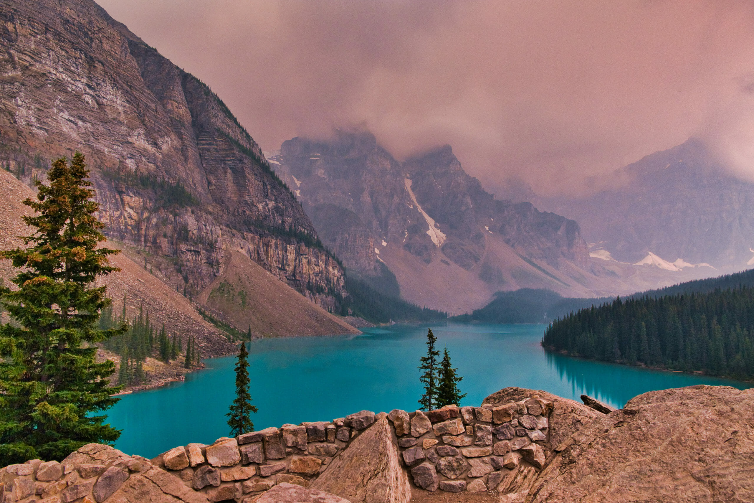 Moraine Lake as seen from Rockpile Trail in summer with reddish-brown skies from sunset and smoky skies from wildfires